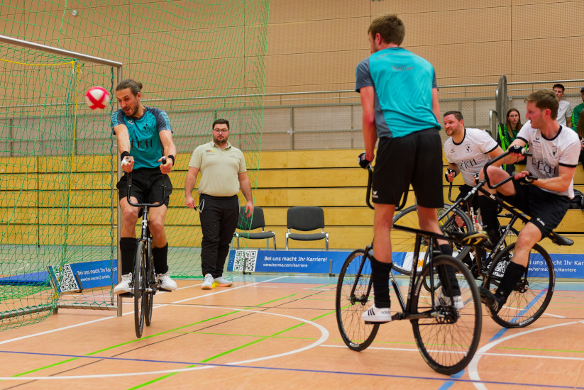 Martin Egarter und Thomas Kieferle führen während eines Radballspiels einen Eckstoß gegen Lukas Keller und Andreas Pongratz aus.
