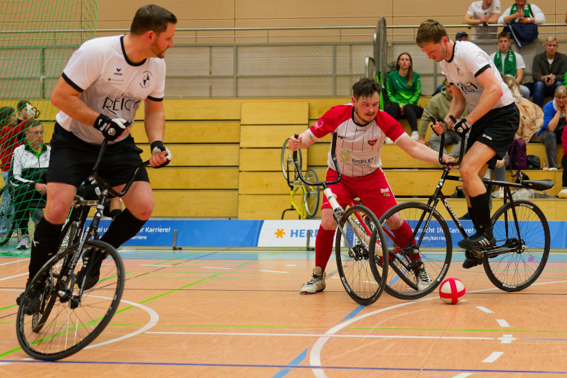 Martin Egarter und Thomas Kieferle während eines Radballspiels, bei dem Thomas Kieferle gerade von einem Gegenspieler gefoult wird.
